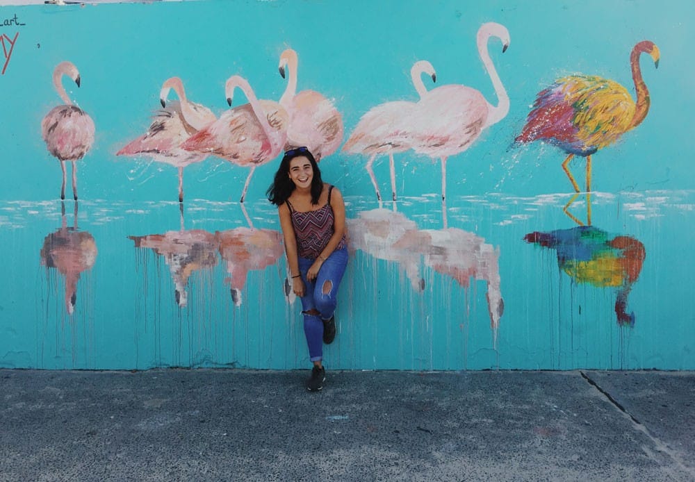 Experiencia Judit chica morena sonriendo a cámara y detrás una pared con dibujos de cigüeñas